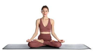 Spor kıyafetli genç bir kadın beyaz arka planda yoga yapıyor.
