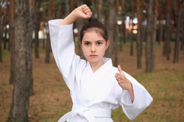 Kimonolu tatlı küçük kız ormanda karate yapıyor.