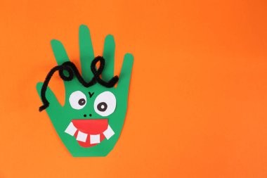 Turuncu arka planda yeşil elli komik bir canavar. Üstü açık, mesaj için yeri var. Cadılar Bayramı dekorasyonu