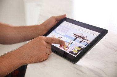 Tablet 'ten online bilet ayırtan adam, yakın plan. Seyahat acentası kavramı