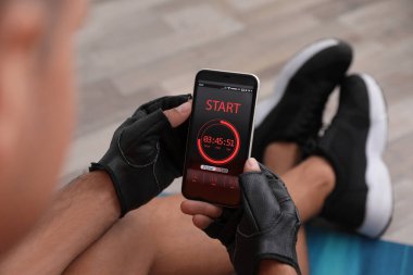 Akıllı telefondaki fitness uygulamasını kullanan adam kapalı mekanda, yakın plan