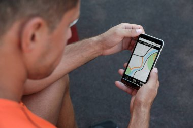Dışarıdaki akıllı telefondan fitness uygulaması kullanan adam, yakın plan.