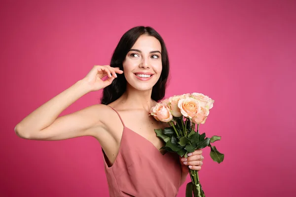 ピンクの背景に美しい花束を持つ笑顔の女性の肖像 — ストック写真