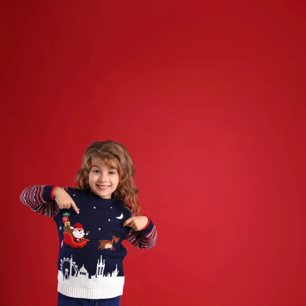 Linda Niña Apuntando Suéter Navidad Contra Fondo Rojo Espacio Para — Foto de Stock