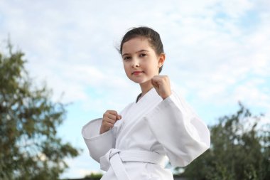 Kimonolu şirin kız dışarıda karate yapıyor.