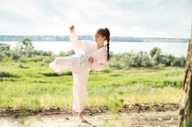 Kimonolu şirin kız dışarıda karate yapıyor.