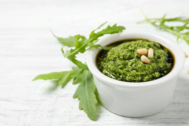 Beyaz ahşap masada bir kase lezzetli pesto ve roka.