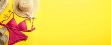 Sarı arka planda güzel pembe bikini ve plaj aksesuarları, düz yatış. Metin için boşluk