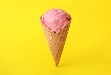 Sarı arka planda waffle külahında leziz pembe dondurma.