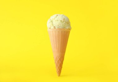 Sarı arka planda waffle külahında leziz dondurma.
