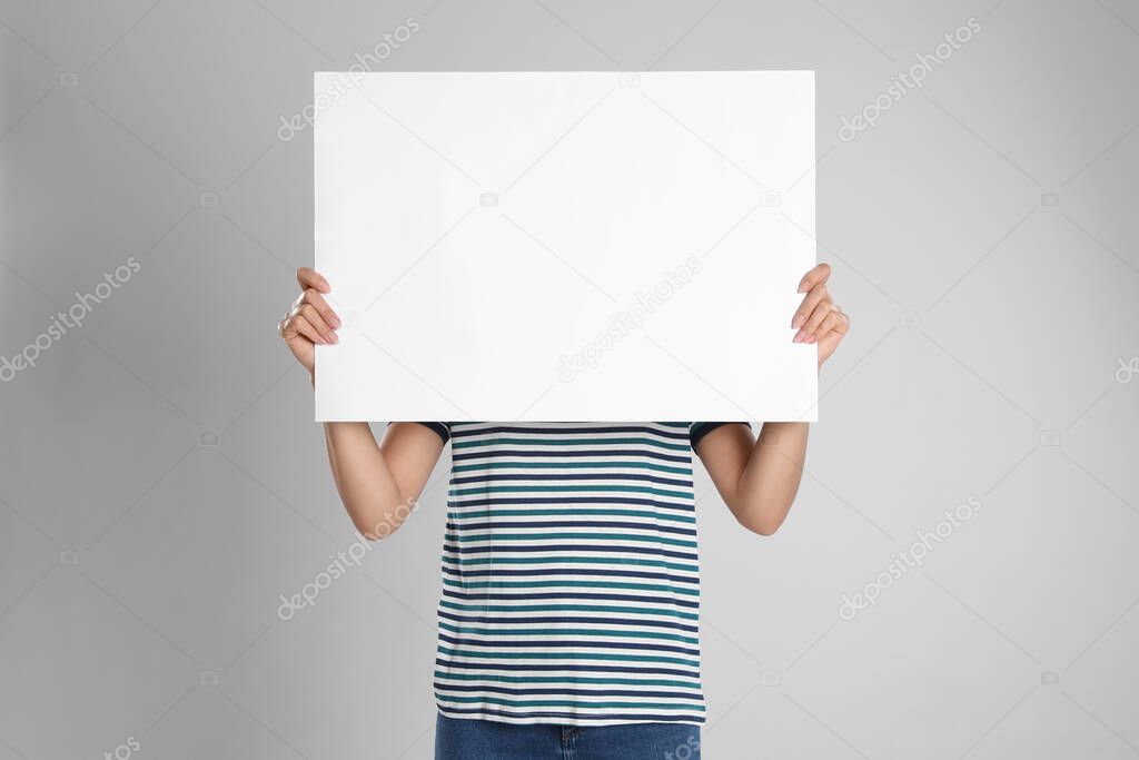 Woman holding blank poster on light grey background