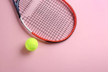 Tenis raketi ve top pembe arka planda, düz yerde. Metin için boşluk