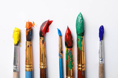 Beyaz arka planda renkli boyalı fırçalar, düz bir zemin