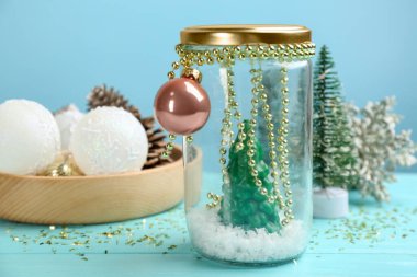 El yapımı kar küresi ve Noel süslemeleri masada.