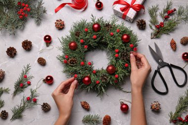 Çiçekçi gri masada güzel bir Noel çelengi yapıyor.