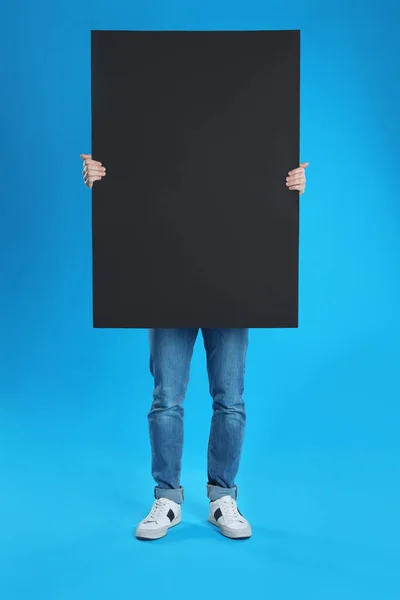 Man holding blank poster on blue background