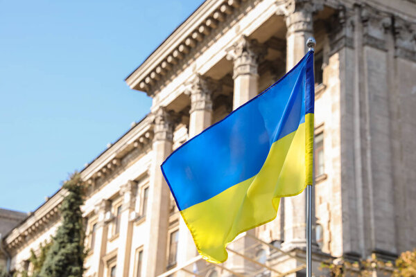 National flag of Ukraine fluttering near building on sunny day