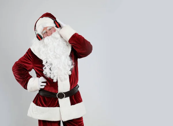 Kulaklıklı Noel Baba Açık Gri Arka Planda Noel Müziği Dinliyor — Stok fotoğraf