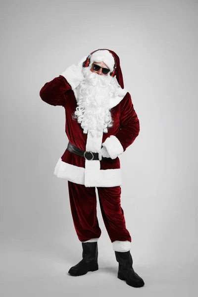 Święty Mikołaj Słuchawkami Słuchającymi Świątecznej Muzyki Jasnoszarym Tle — Zdjęcie stockowe