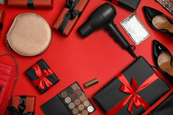 Gift boxes, cosmetics, hairdryer, shoes and women's accessories on red background, flat lay. Space for text