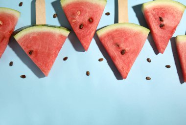 Açık mavi arka planda olgun karpuz dilimleri, düz. Metin için boşluk