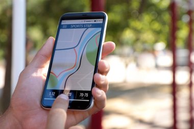 Dışarıdaki akıllı telefondan fitness uygulaması kullanan adam, yakın plan.