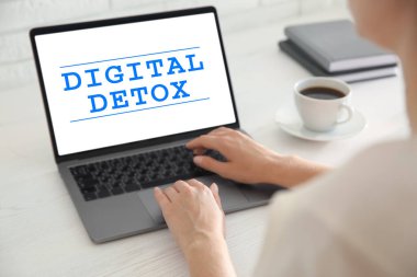Masada dizüstü bilgisayarı olan bir kadın Dijital Detox kullanıyor.
