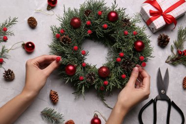 Çiçekçi gri masada güzel bir Noel çelengi yapıyor.