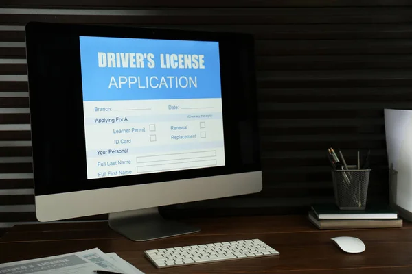 Computer with driver\'s license application form on table in office