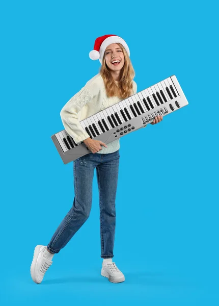Junge Frau Mit Weihnachtsmütze Und Synthesizer Auf Hellblauem Hintergrund Weihnachtsmusik — Stockfoto
