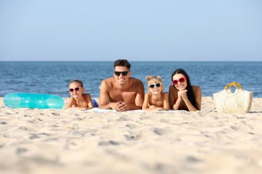 Denize yakın kumsalda mutlu bir aile. Yaz tatili