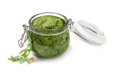 Lezzetli roka pesto kavanozu ve beyaz arka planda malzemeler.