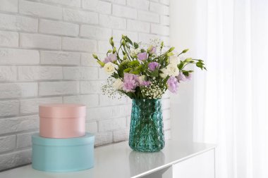 Beyaz tuğla duvarın yanındaki dolapta güzel Eustoma çiçekleri var.