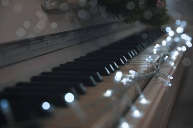 İçerideki piyano tuşlarında parlayan peri ışıkları, yakın plan. Noel müziği