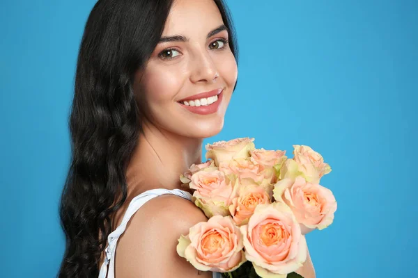 明るい青の背景に美しい花束を持つ笑顔の女性の肖像画 — ストック写真