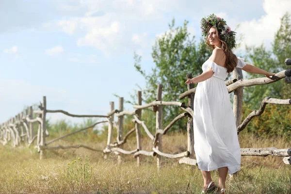 Young Woman Wearing Wreath Made Beautiful Flowers Wooden Fence Sunny — Stock Photo, Image