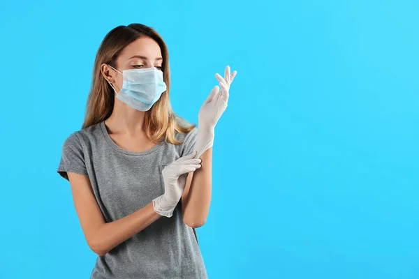 Young Woman Protective Mask Putting Medical Gloves Light Blue Background — Stock Photo, Image