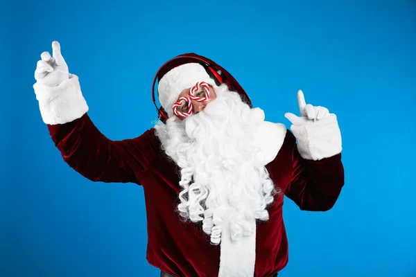 圣诞老人 带着耳机 在蓝色背景下听圣诞音乐 — 图库照片