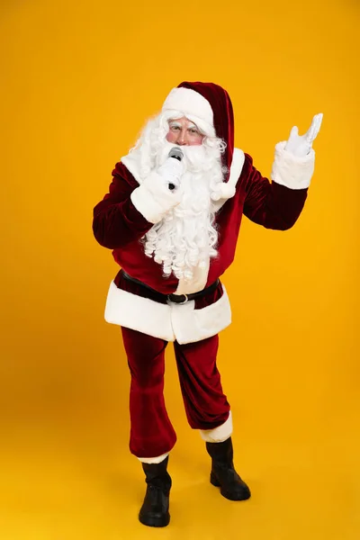 圣诞老人用黄色背景的话筒唱歌 圣诞音乐 — 图库照片