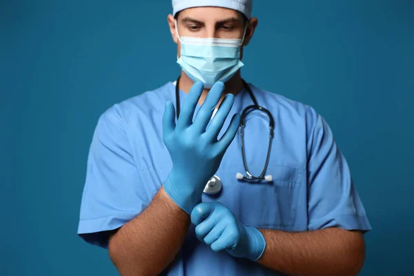 Врач Защитной Маске Надевает Медицинские Перчатки Синий Фон — стоковое фото