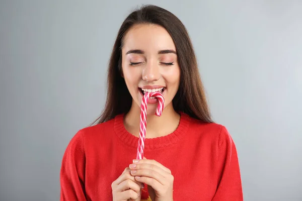 Young Woman Christmas Sweater Eating Candy Cane Grey Background — Stock Photo, Image