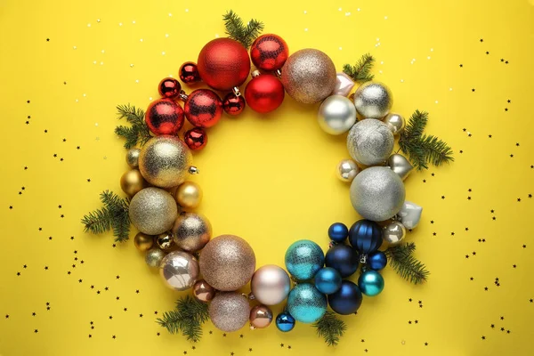 Heldere Feestelijke Krans Gemaakt Van Kerstballen Sparren Takken Gele Achtergrond — Stockfoto
