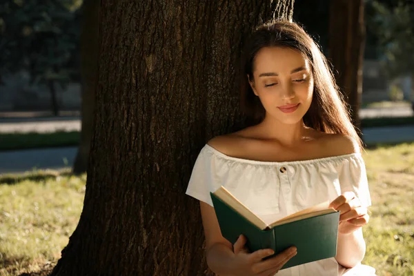 Parkta Ağacın Yanında Kitap Okuyan Güzel Bir Kadın — Stok fotoğraf