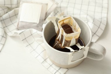 Beyaz ahşap masaya damlayan kahve torbası, yakın plan.