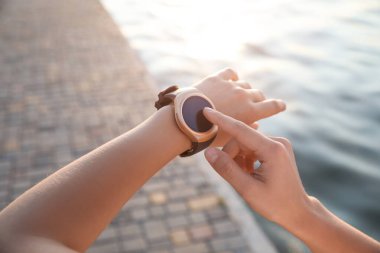 Nehir kenarındaki eğitimden sonra kadın fitness takip cihazını kontrol ediyor.