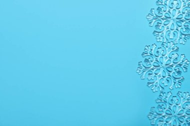Açık mavi zemin üzerinde güzel dekoratif kar taneleri, düz uzanmış. Metin için boşluk