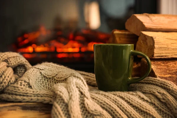 暖炉に対してテーブルの上に熱い飲み物や毛布と緑のカップ — ストック写真