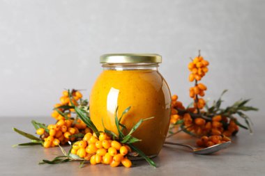 Lezzetli deniz dikeni reçeli ve gri masada taze böğürtlen.