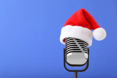 Mavi arka planda Noel Baba şapkalı Retro mikrofon, mesaj için boşluk. Noel müziği