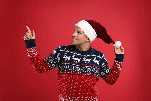 Hombre Guapo Jersey Navidad Sombrero Santa Señalando Sobre Fondo Rojo — Foto de Stock